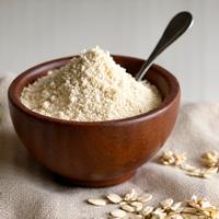 Bowl of oat extract powder with a spoon, symbolizing soothing properties.